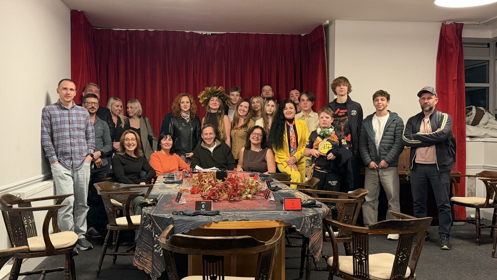 Guests at a Fortuna Community meeting standing together in front of a red curtain