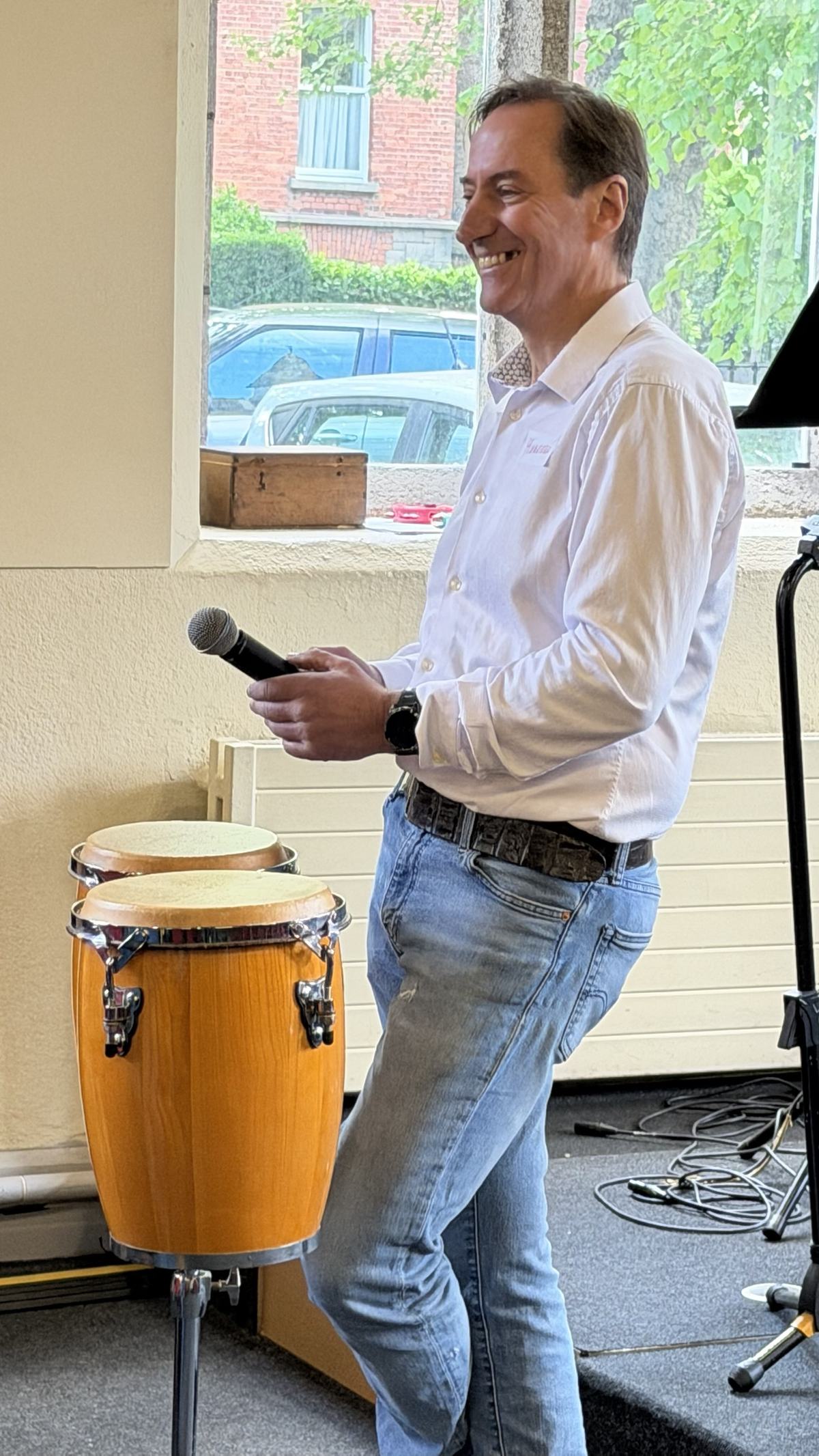A host with a microphone next to a drum at Networking & Friends