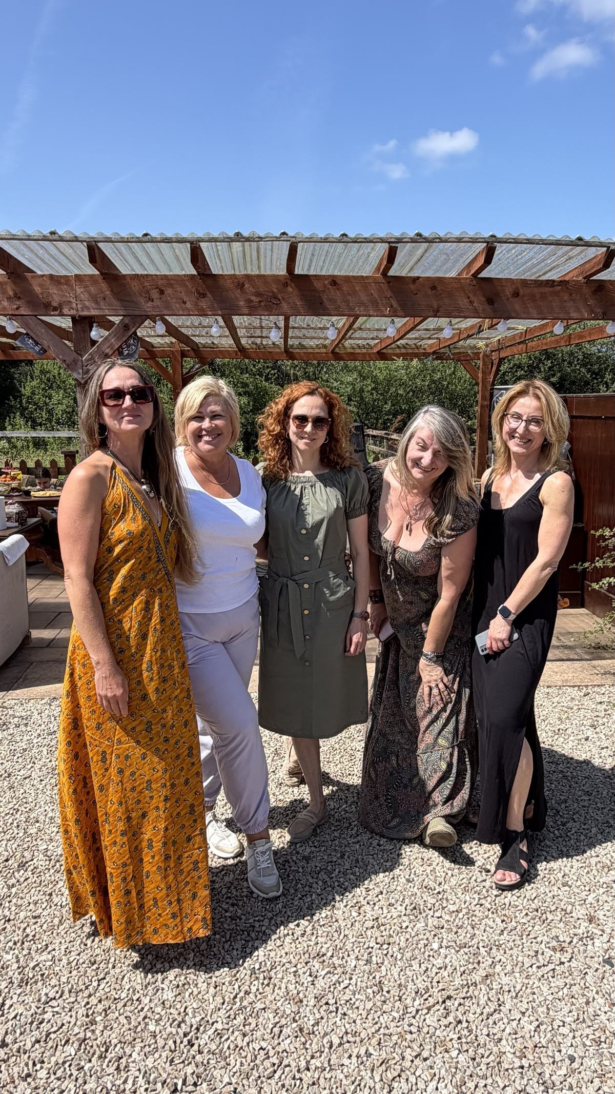 Five women posing together in the sun at the picnic