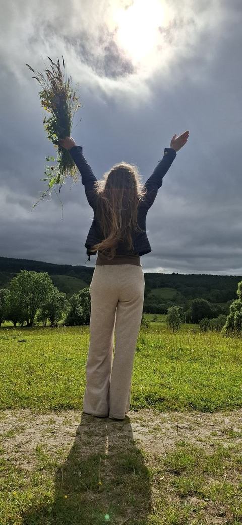 A guest raising her arms to the sky on a hill under clouds