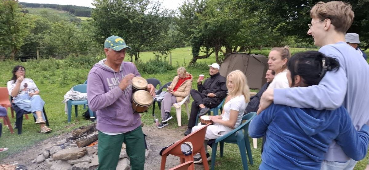 Guests sitting in a circle on the grass, one playing a drum