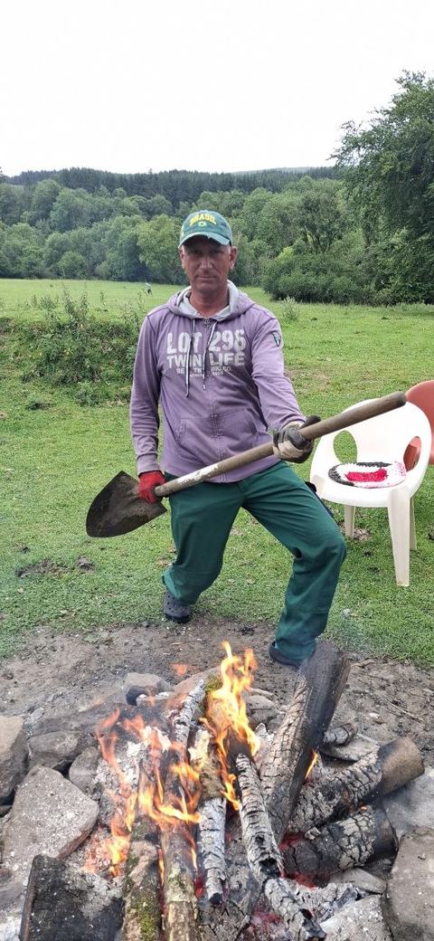 A guest tending a campfire in a green field